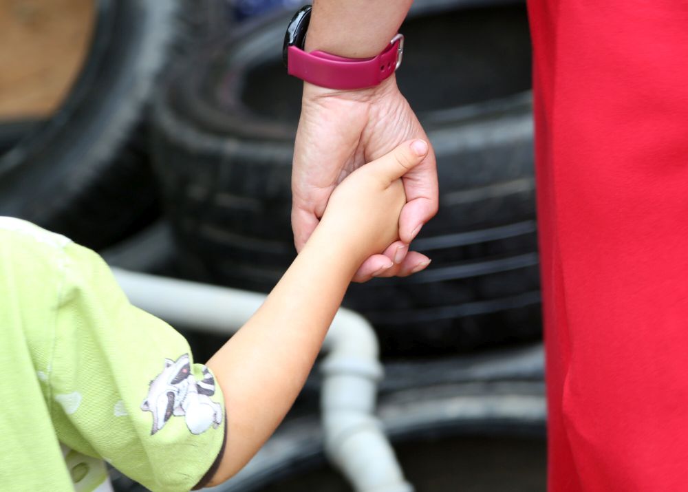Kind und Erwachsene halten sich an der Hand