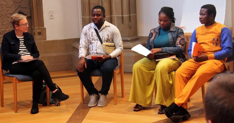 Vier Leute in einem  Stuhlkreis in einer Kirche, einer spricht, die anderen hören zu.